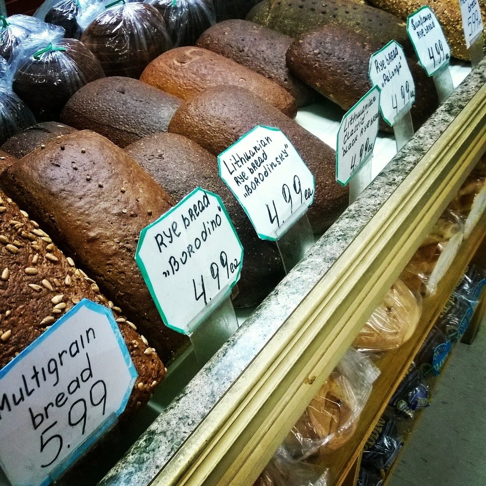 Bakery shelf with dark rye loaves and handwritten price cards